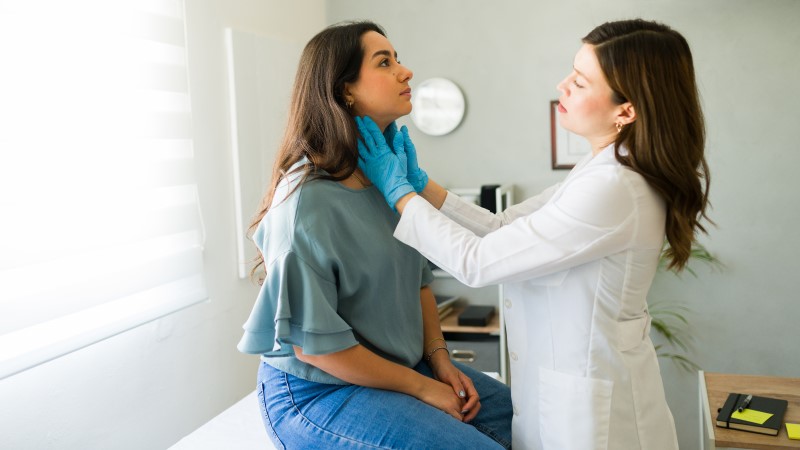 Zdjęcie przedstawia pacjenta podczas konsultacji lekarskiej, gdzie może być diagnozowana angina paciorkowcowa. Jest to infekcja bakteryjna powodowana przez paciorkowce grupy A. Objawy obejmują gorączkę, ból gardła, powiększone migdałki i węzły chłonne. Leczenie zazwyczaj polega na podawaniu antybiotyków. W przypadku podejrzenia anginy paciorkowcowej ważna jest konsultacja z lekarzem.