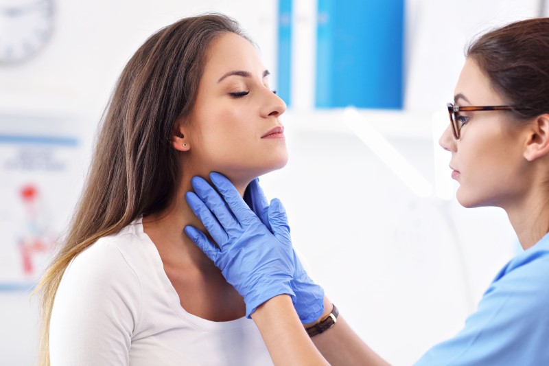 Badanie szyi podczas konsultacji lekarskiej, ilustrujące diagnostykę powiększonych węzłów chłonnych.